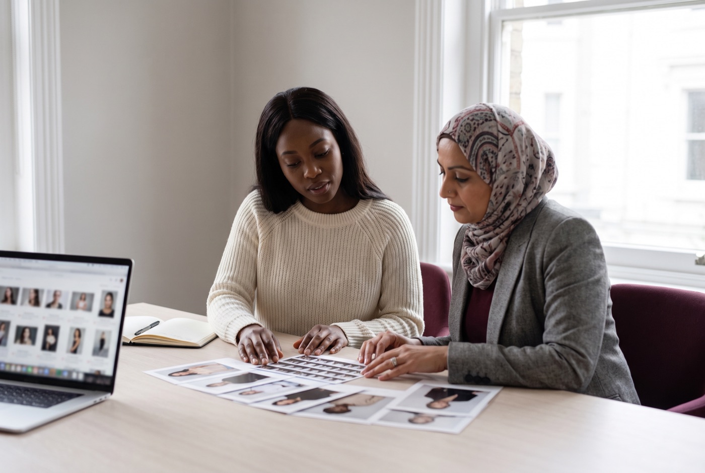 Two bookers comparing model cards in a London modelling agency office