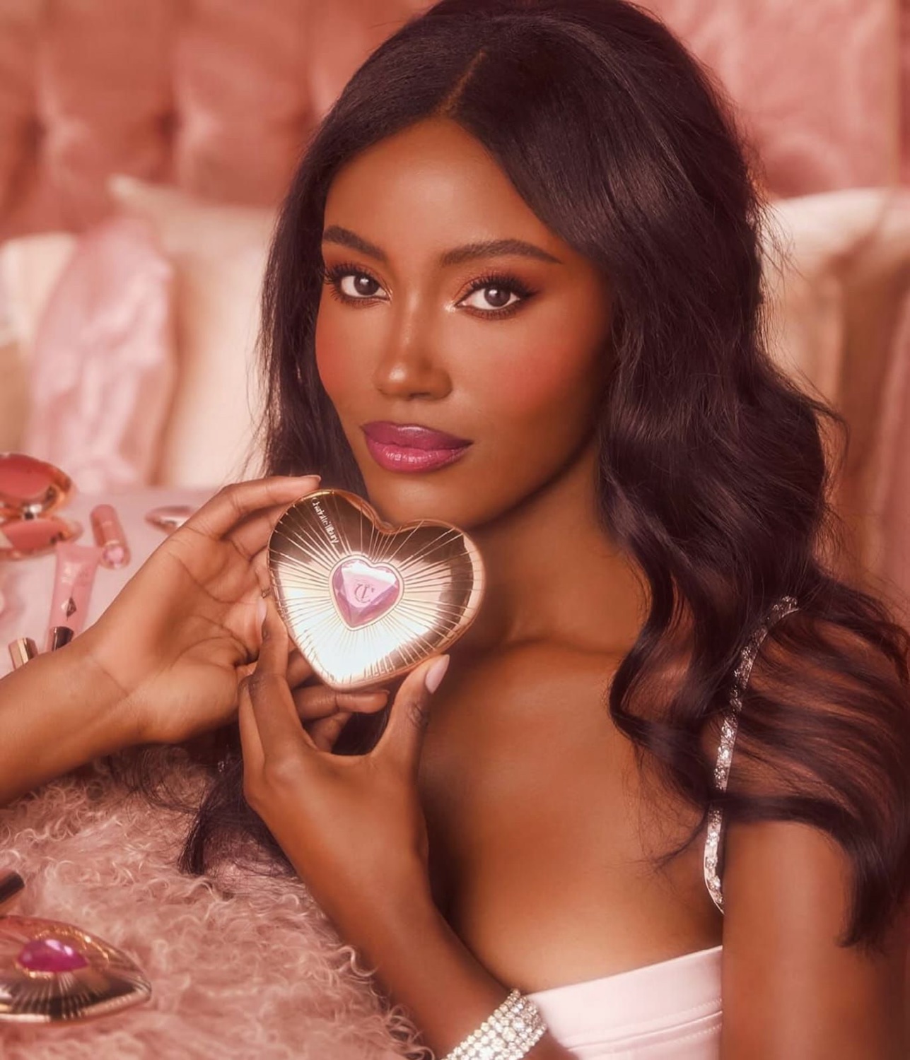 Black model in a glam beauty campaign holding a highlighter compact