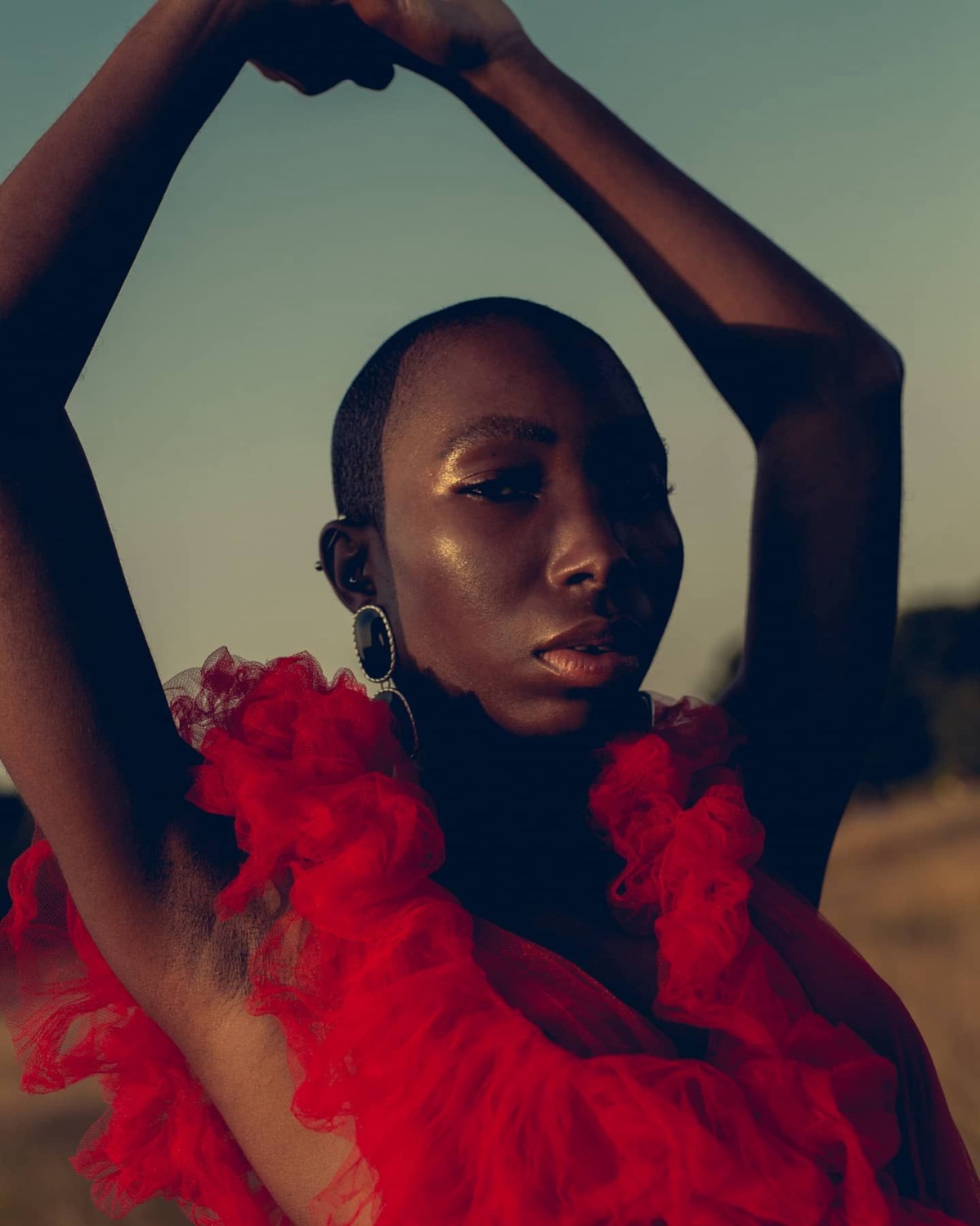 Black model in a red editorial look, golden-hour beauty shot