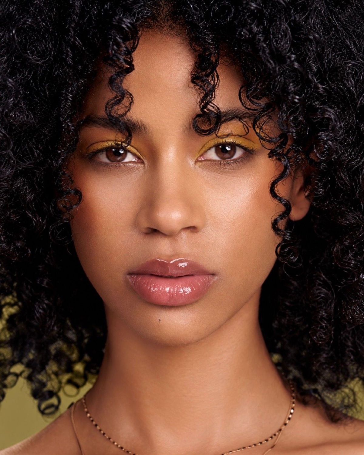 Black model beauty close-up with natural curly hair and bold eye makeup