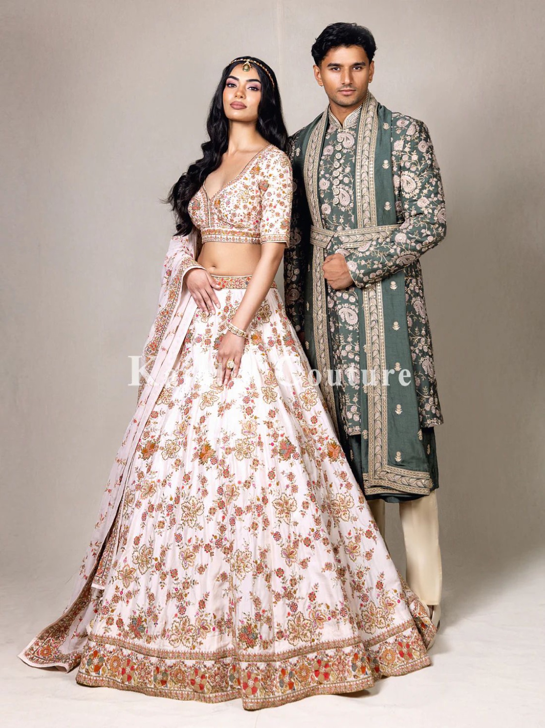 South Asian bridal couple — woman in a pink lehenga, man in a green sherwani